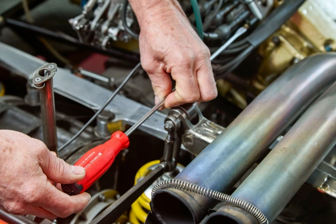 Mechanic working on car engine with tools